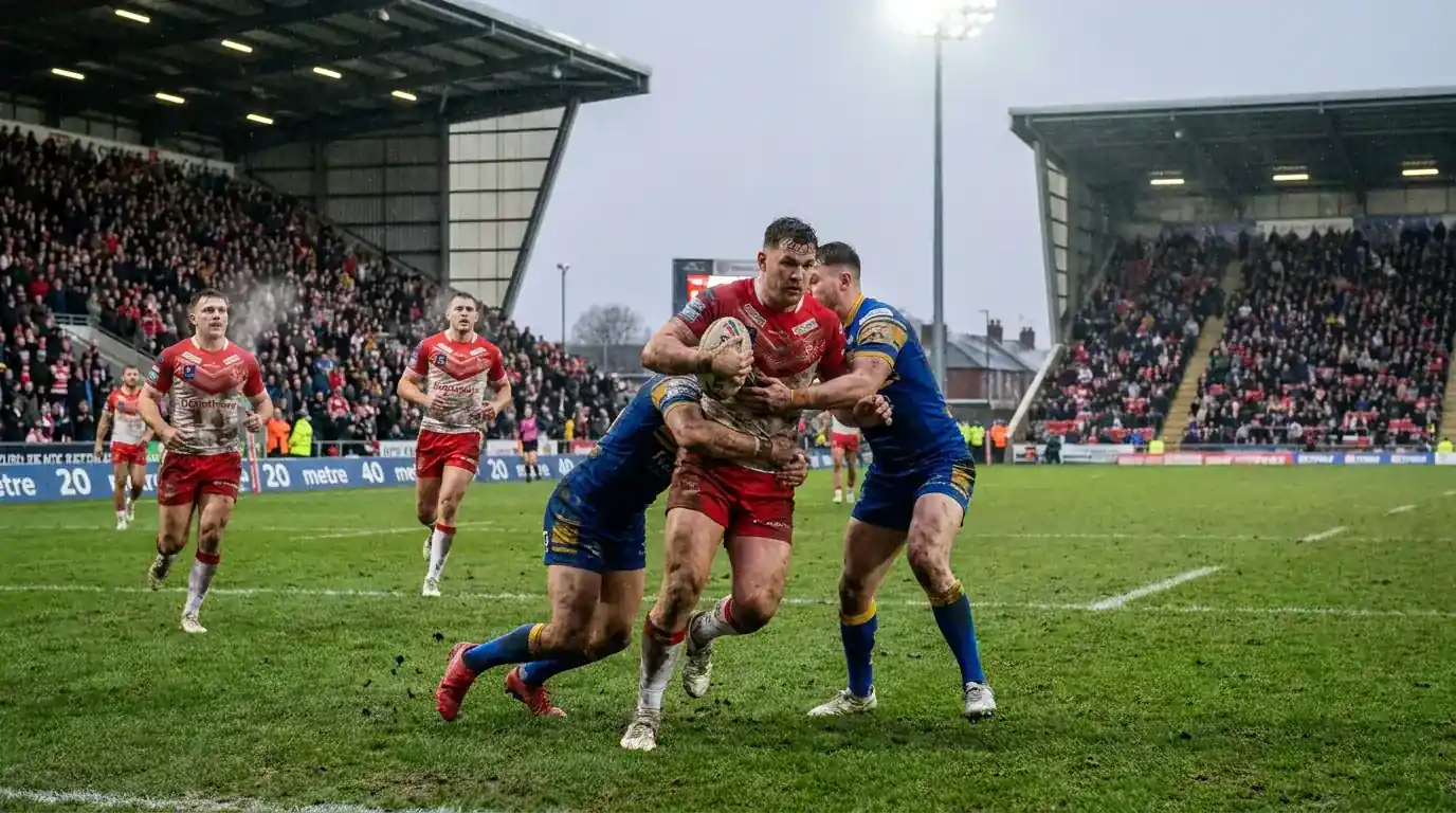 Rugby league players competing in a Super League match with a packed northern England ground behind them