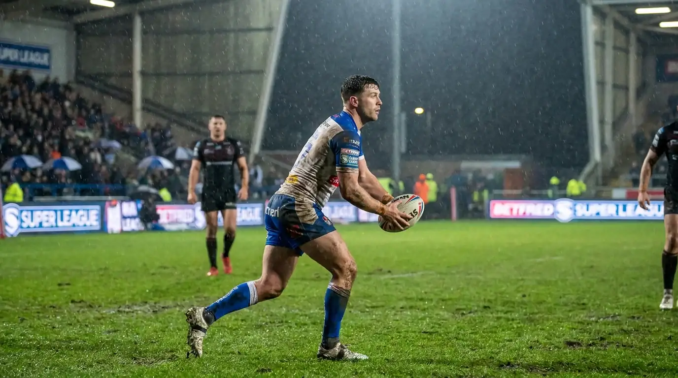 Rugby league halfback preparing to kick for field position during a rainy evening Super League fixture
