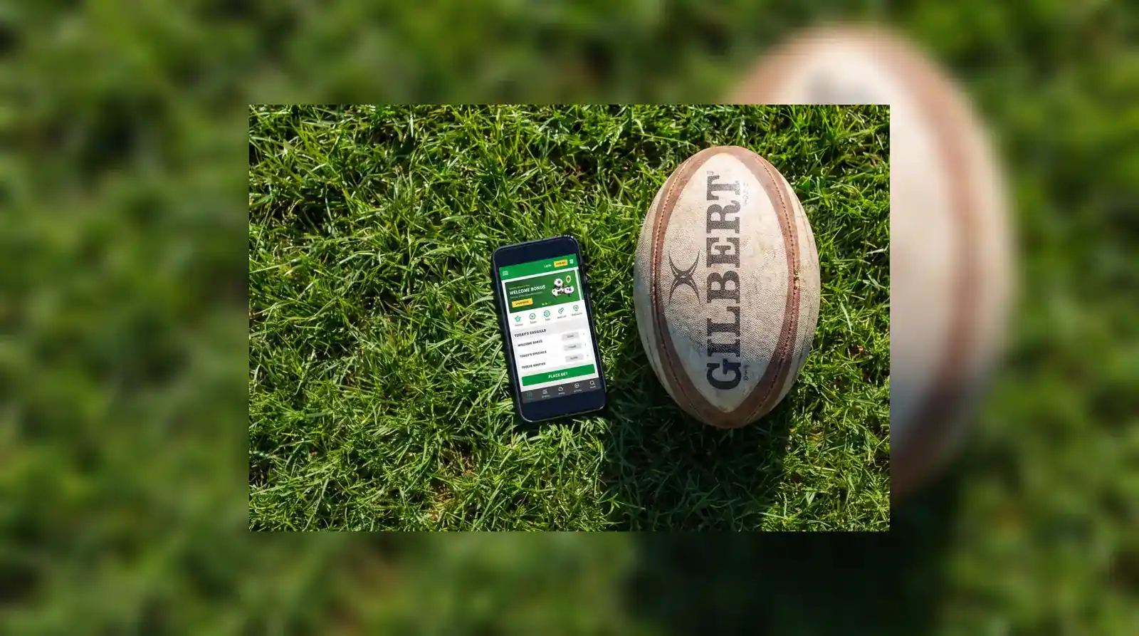Smartphone displaying a rugby betting app welcome offer screen next to a rugby ball on grass