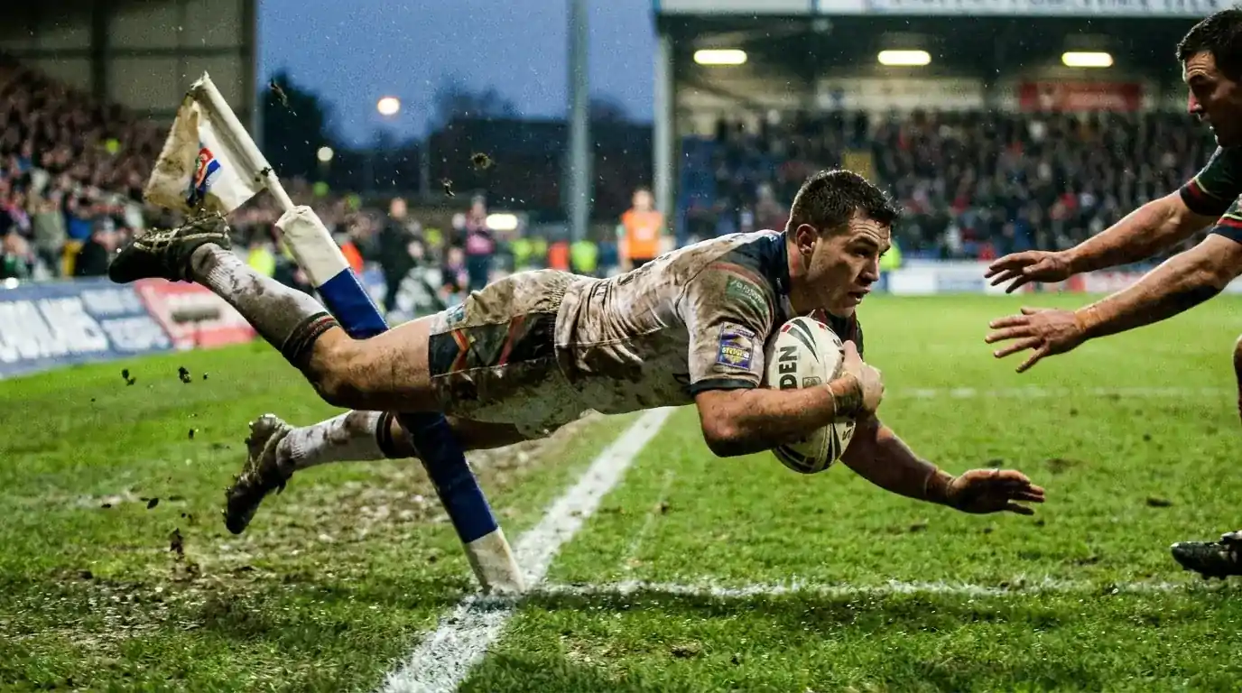 Rugby league winger diving to score a try in the corner during a Super League match