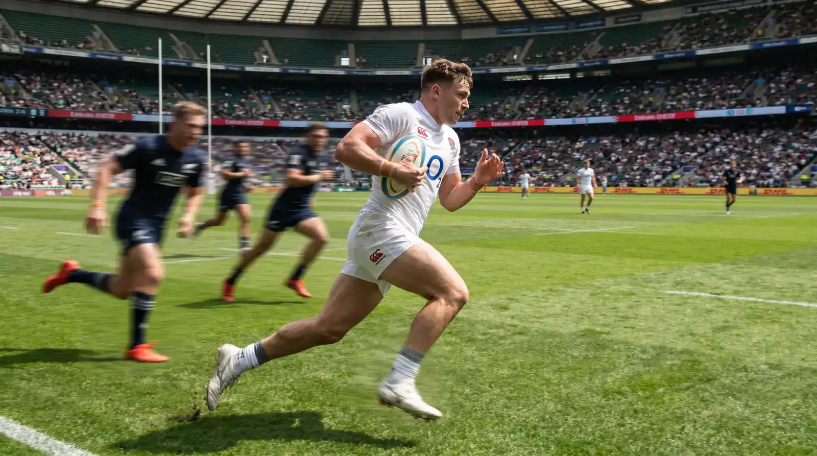 Sevens rugby player sprinting through open space on a full-size pitch with few defenders